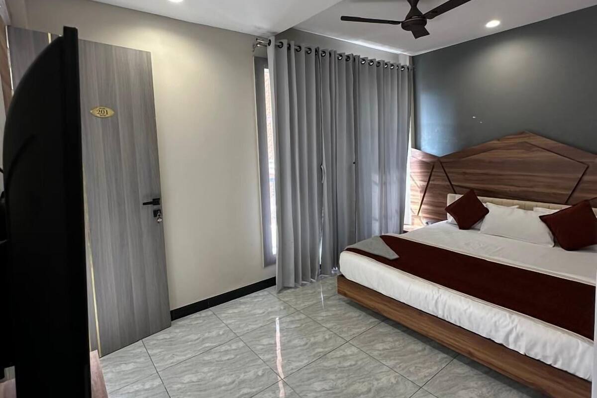 A modern bedroom with a bed, curtains, a ceiling fan, and a door.