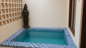 Ein kleiner, gefliester Pool mit einer Statue in der Ecke.