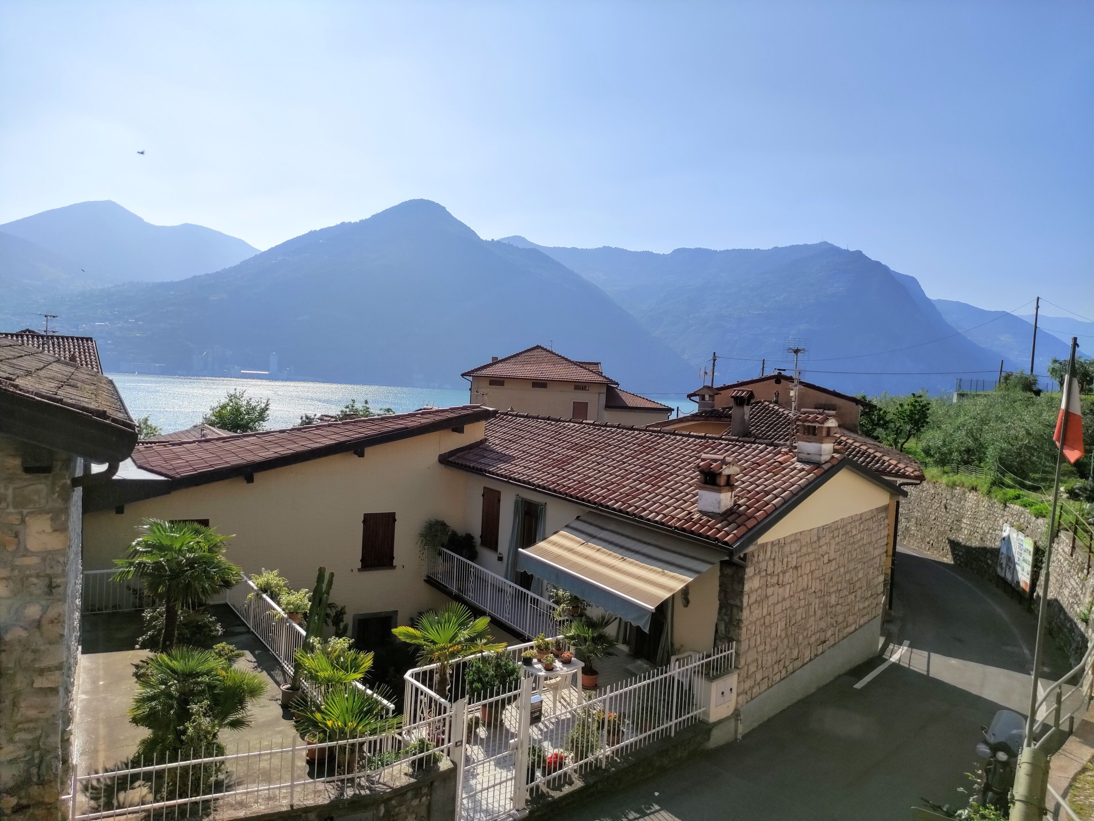 A traditional building with a tiled roof, a courtyard with potted plants, and a view of a lake and mountains in the background.
