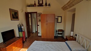 A bedroom with a large bed, a wooden wardrobe, a television, and a desk with a chair. - Dimora Fenni – Historic elegance and modern comfort in the heart of Monte Isola (Monte Isola)