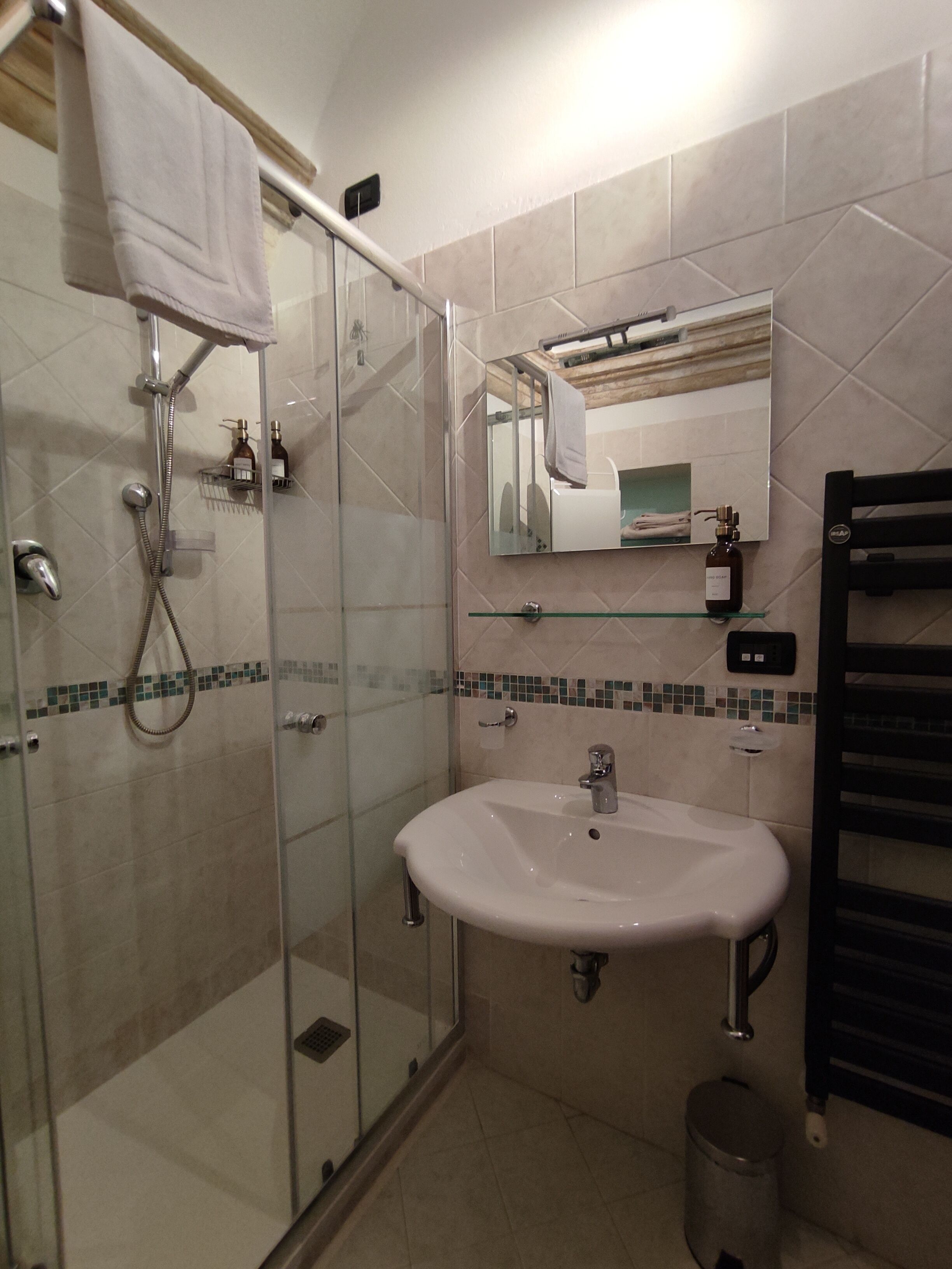 Une salle de bain moderne avec une douche à parois de verre, un lavabo blanc et un miroir au-dessus.