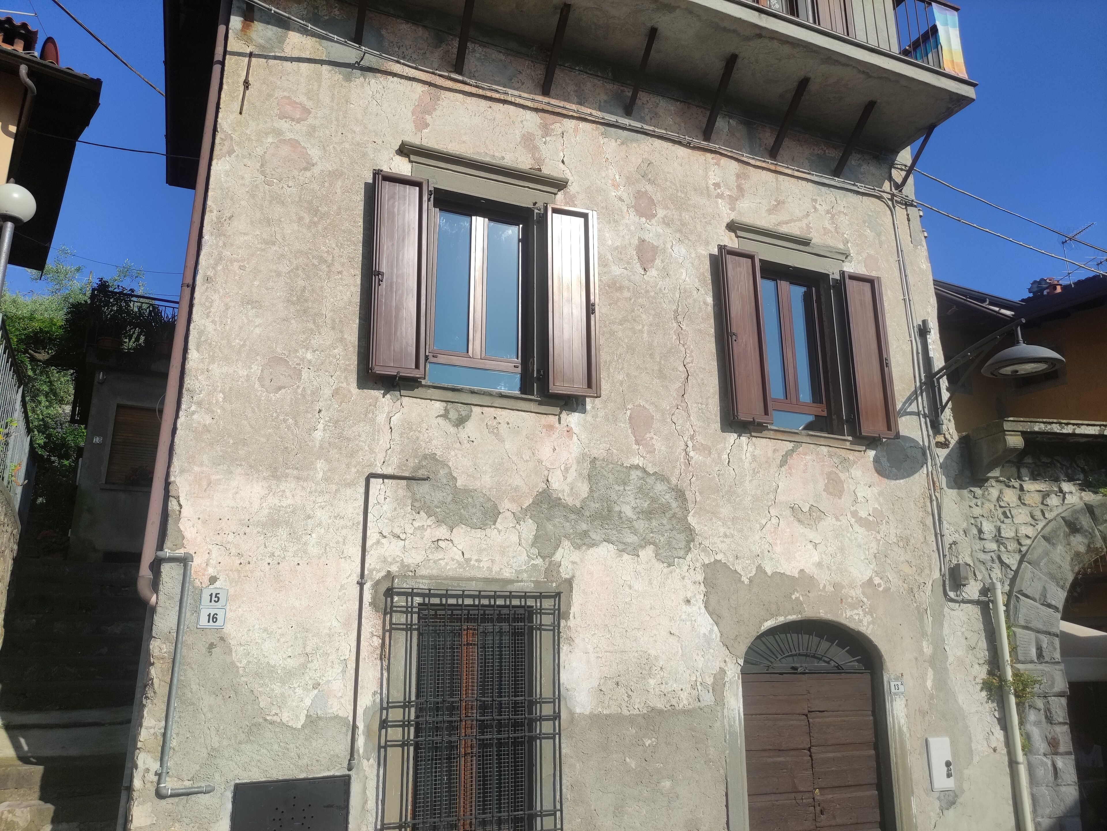 A two-story building with a weathered facade, a balcony with a railing, and a door with a metal gate.