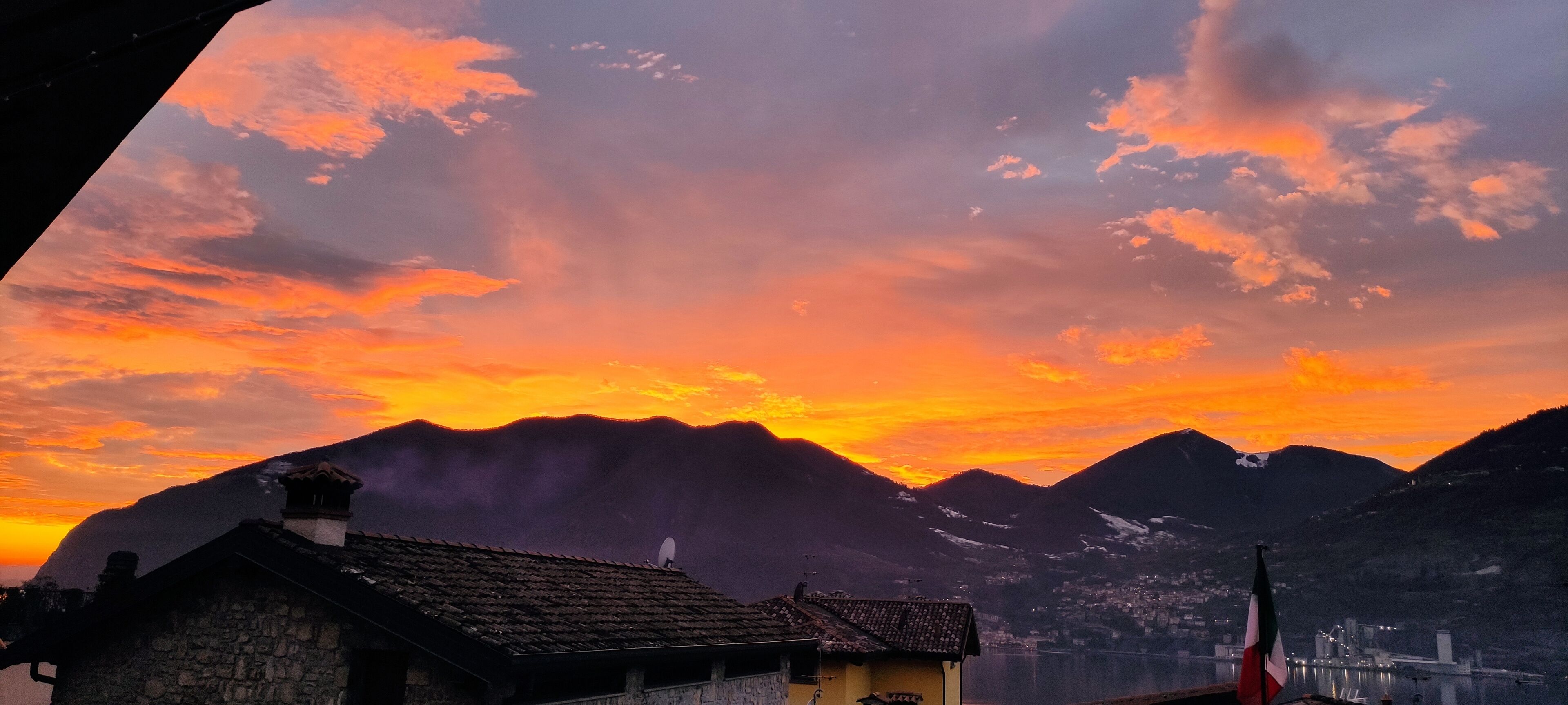 Eine Berglandschaft bei Sonnenuntergang, mit einer Flagge und einem Gewässer.