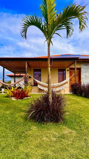A house with a covered patio, a hammock, and a palm tree in the yard. - Villa Pérola do Aré · Heated and private Pool & Jacuzzi · Barbecue area (Armação dos Búzios)