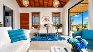 Una sala de estar moderna con comedor, cocina y vistas al exterior.