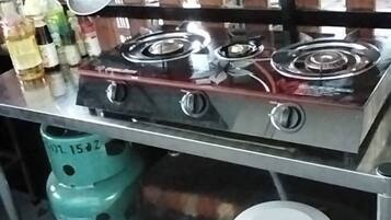 A kitchen area with a gas stove, stainless steel cabinets, and a gas cylinder.