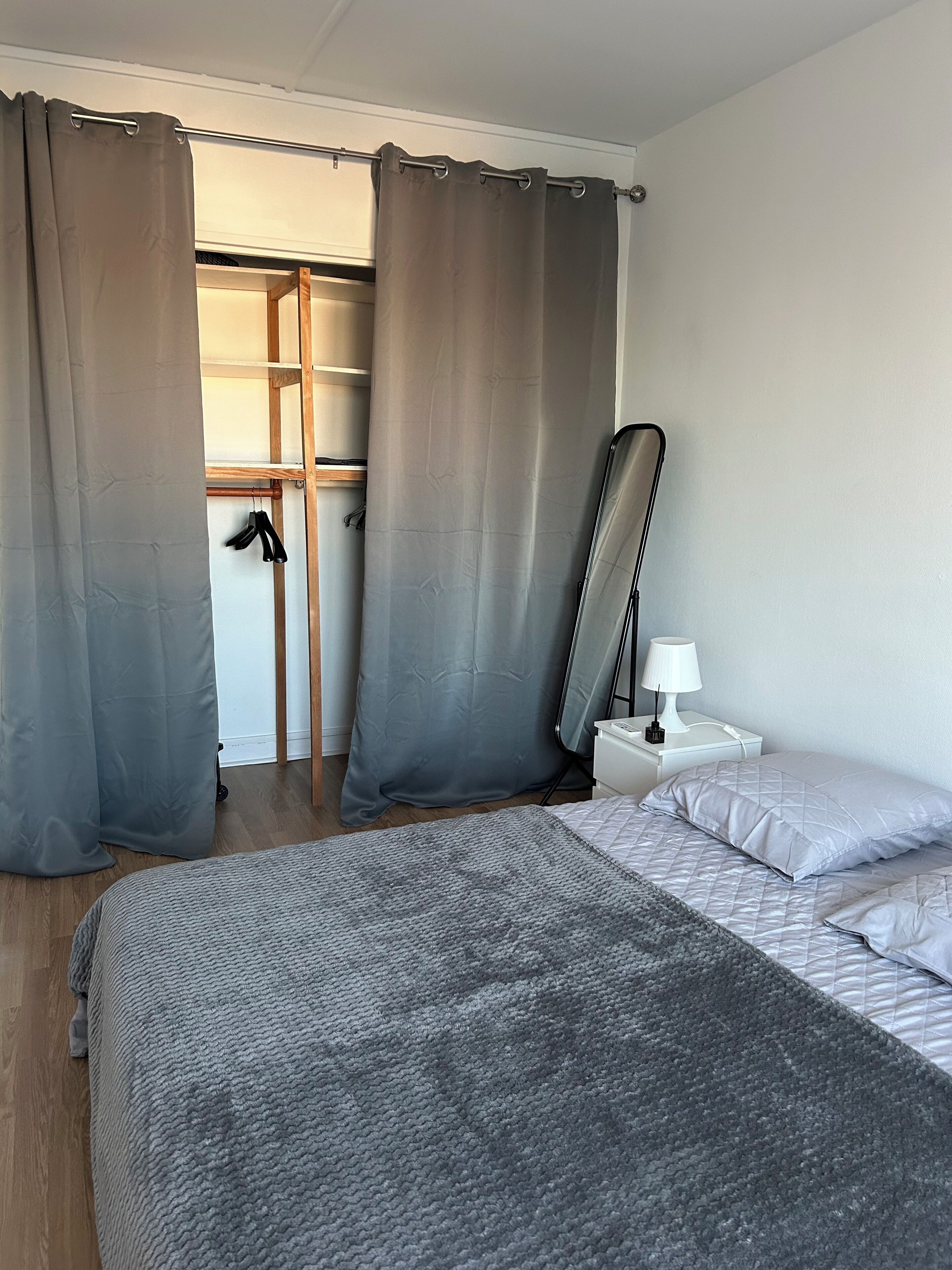 Ein Schlafzimmer mit Bett, Nachttisch, Lampe und Kleiderschrank.