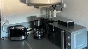 A kitchenette with a coffee maker, toaster, microwave, and a small refrigerator. - Cosy, fully-equipped apartment (Chalon-sur-Saône)