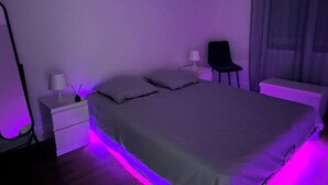 A bedroom with a bed, nightstands, a chair, and a lamp. - Cosy, fully-equipped apartment (Chalon-sur-Saône)