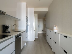 Eine moderne Küche mit weißen Schränken, einer Kaffeemaschine und einem Kühlschrank.
