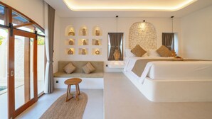 A modern bedroom with a large bed, a seating area with cushions, a wall of decorative vases, and a stone accent wall. - Dianatara Villa Ubud by Dhananjaya Hospitality (Celuk)
