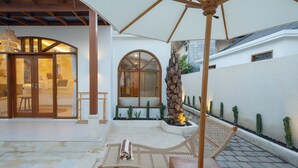 A patio with a hammock, a wooden table, and a ceiling fan. - Dianatara Villa Ubud by Dhananjaya Hospitality (Celuk)