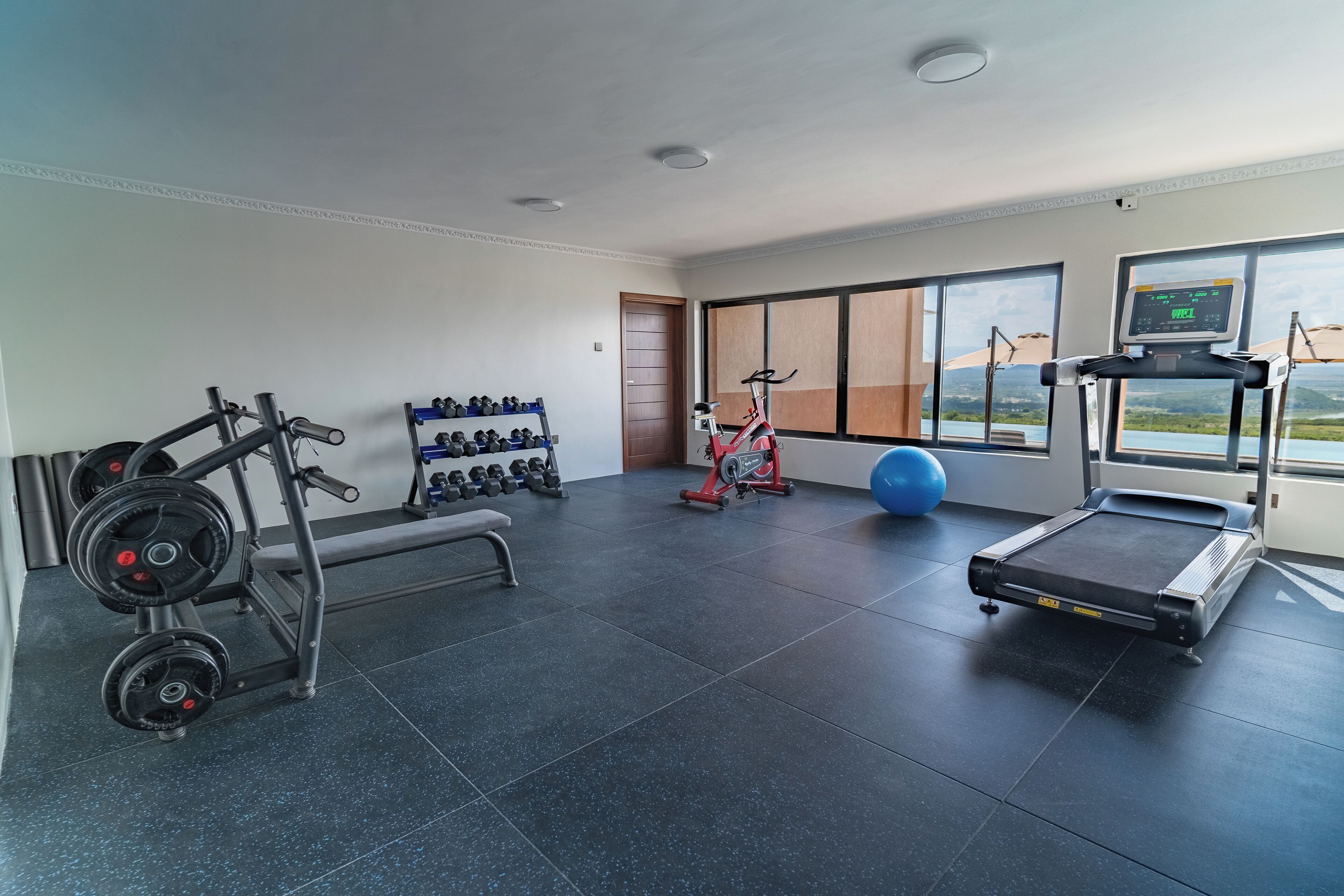 A gym with a treadmill, stationary bike, and weight rack.