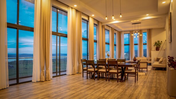A spacious room with large windows, a dining area, and a sofa. - The 67 Escape, Elementaita (Gilgil)
