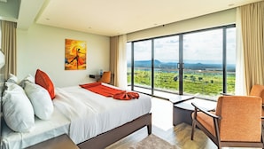 A modern hotel room with a large bed, a view of a green landscape, and a painting on the wall. - The 67 Escape, Elementaita (Gilgil)
