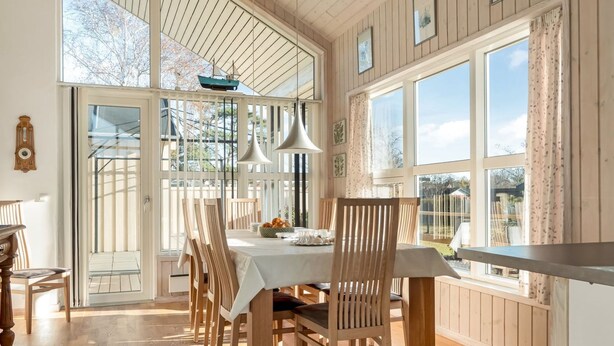 Un comedor con mesa y sillas de madera, ventanas amplias y vistas al exterior.
