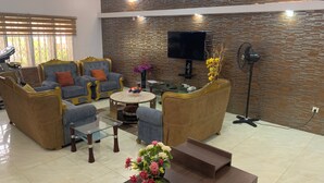 A living room with a sofa set, a coffee table, a TV, and a fan. - Rossy's Apartments Serviced Apts Abuja (Abuja)