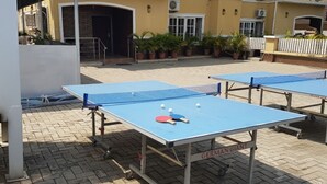 An outdoor ping pong table area with two tables, each with a net and paddles. - Rossy's Apartments Serviced Apts Abuja (Abuja)