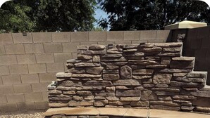 A stone fire pit with a circular design, surrounded by a stone wall and a brick border. - Cozy 4bd3ba Pool/FirePit/BBQ House in Maricopa (Maricopa)