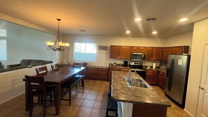 A modern kitchen with wooden cabinets, a granite countertop, and stainless steel appliances. - Cozy 4bd3ba Pool/FirePit/BBQ House in Maricopa (Maricopa)