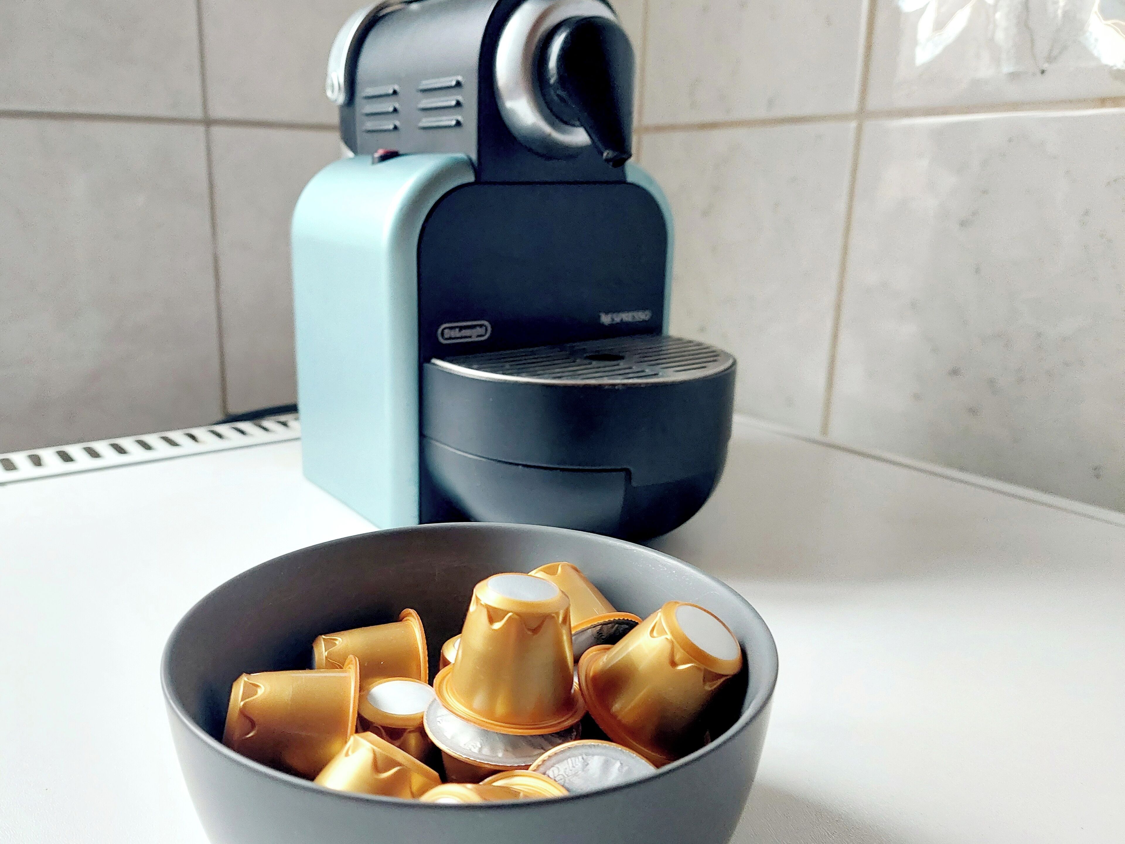 A kitchen with a coffee machine and a bowl of coffee capsules.