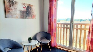 A room with a view of a wooden deck, a painting on the wall, and two chairs with a small table. - Guesthouse Graz Central for 9 People (Graz)