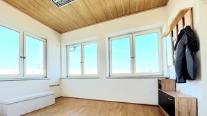 A spacious room with wooden flooring, large windows, and a built-in bench. - Guesthouse Graz Central for 9 People (Graz)