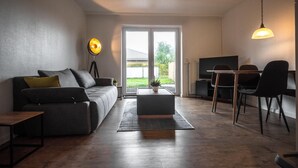 A modern living room with a sofa, coffee table, and dining area. - Cozy vacation home Deichkoje 2 in Dagebüll with terrace and garden (Dagebüll)
