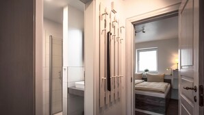 A modern bedroom with a large bed, a walk-in closet, and a bathroom with a glass shower. - Cozy vacation home Deichkoje 2 in Dagebüll with terrace and garden (Dagebüll)