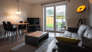 Ein modernes Wohnzimmer mit Sofa, Couchtisch, Fernseher und Essbereich.