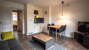 Ein modernes Wohnzimmer mit einer Couch, einem Couchtisch, einem Esstisch, Stühlen und einem Fernseher.