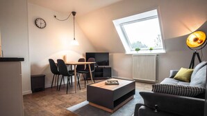 Un salon moderne avec un coin repas, une grande fenêtre et un téléviseur.