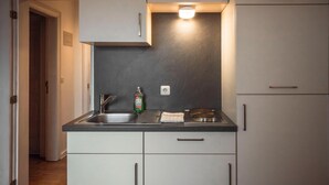 A compact kitchen with a sink, countertop, and cabinets.