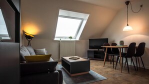 A modern loft apartment with a skylight, a dining area, and a living room with a sofa and coffee table. - Apartment Deichkoje 4 in Dagebüll, featuring modern amenities and a location near the North Sea (Dagebüll)