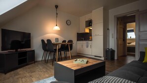 A modern living room with a flat-screen TV, a wooden coffee table, a sofa, and a dining area with chairs and a small table. - Apartment Deichkoje 4 in Dagebüll, featuring modern amenities and a location near the North Sea (Dagebüll)