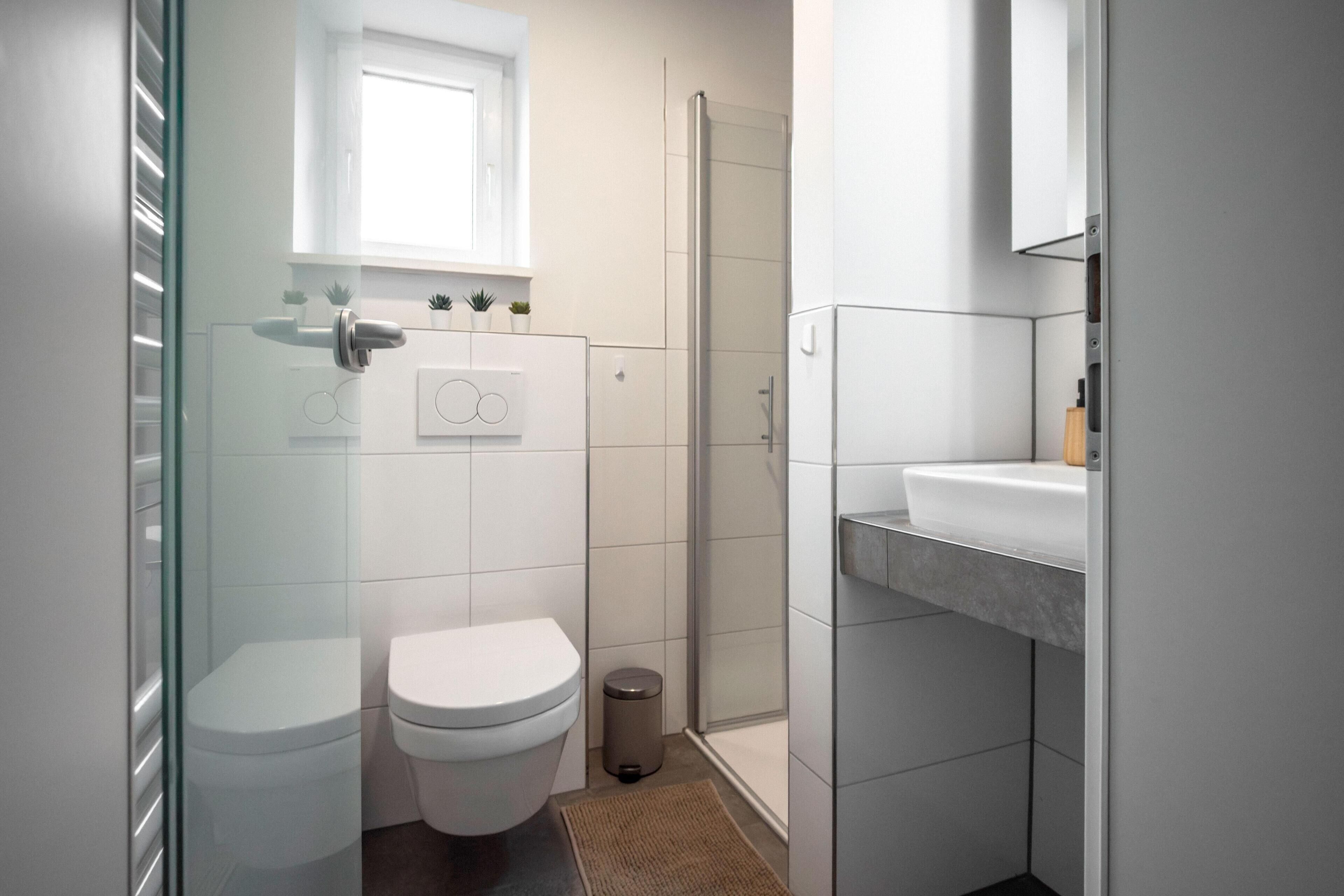 A modern bathroom with a toilet, sink, and shower.