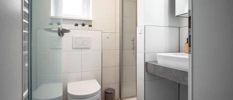 A modern bathroom with a toilet, sink, and shower.