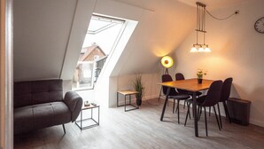 Eine moderne Loftlösung mit Essbereich, einer Couch, einem kleinen Tisch und einer Topfpflanze.