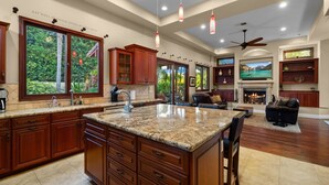 A spacious kitchen with granite countertops, wooden cabinets, and a large island. - Tuscan Sands by Coastline Vacation Rentals (San Diego)