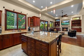 A spacious kitchen with granite countertops, wooden cabinets, and a large island. - Tuscan Sands by Coastline Vacation Rentals (San Diego)