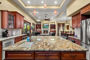 A spacious kitchen with granite countertops, wooden cabinets, and a central island. - Tuscan Sands by Coastline Vacation Rentals (San Diego)
