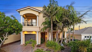 A two-story house with a balcony, a garage, and a well-maintained garden with palm trees and shrubs. - Tuscan Sands by Coastline Vacation Rentals (San Diego)