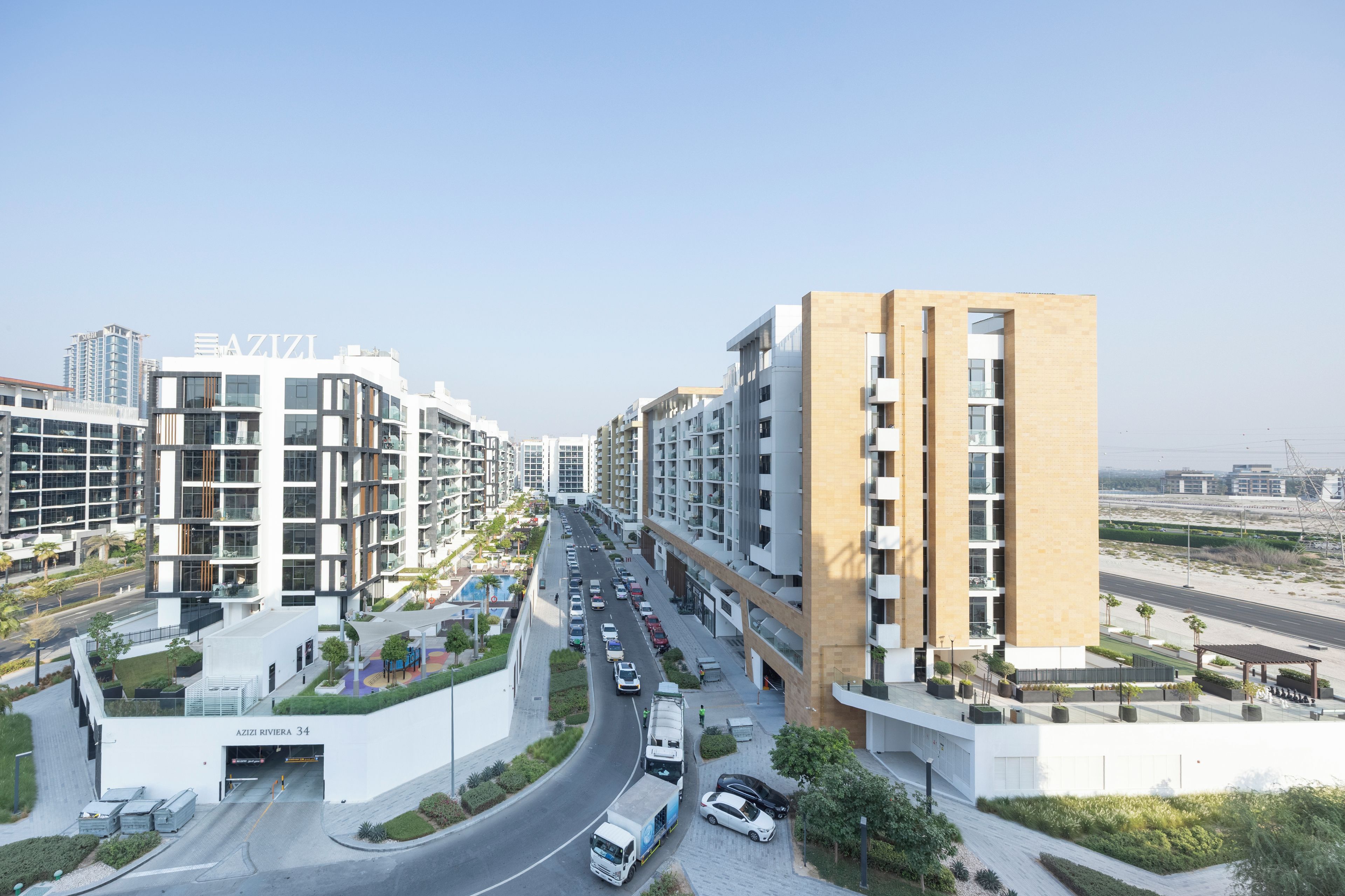 A modern residential building with a multi-level structure, a covered parking area, and a clear road in front.