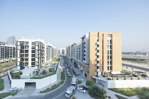 A modern residential building with a multi-level structure, a covered parking area, and a clear road in front. - Bloomfields 1BR in Azizi Riviera 33 - Meydan (Dubai)