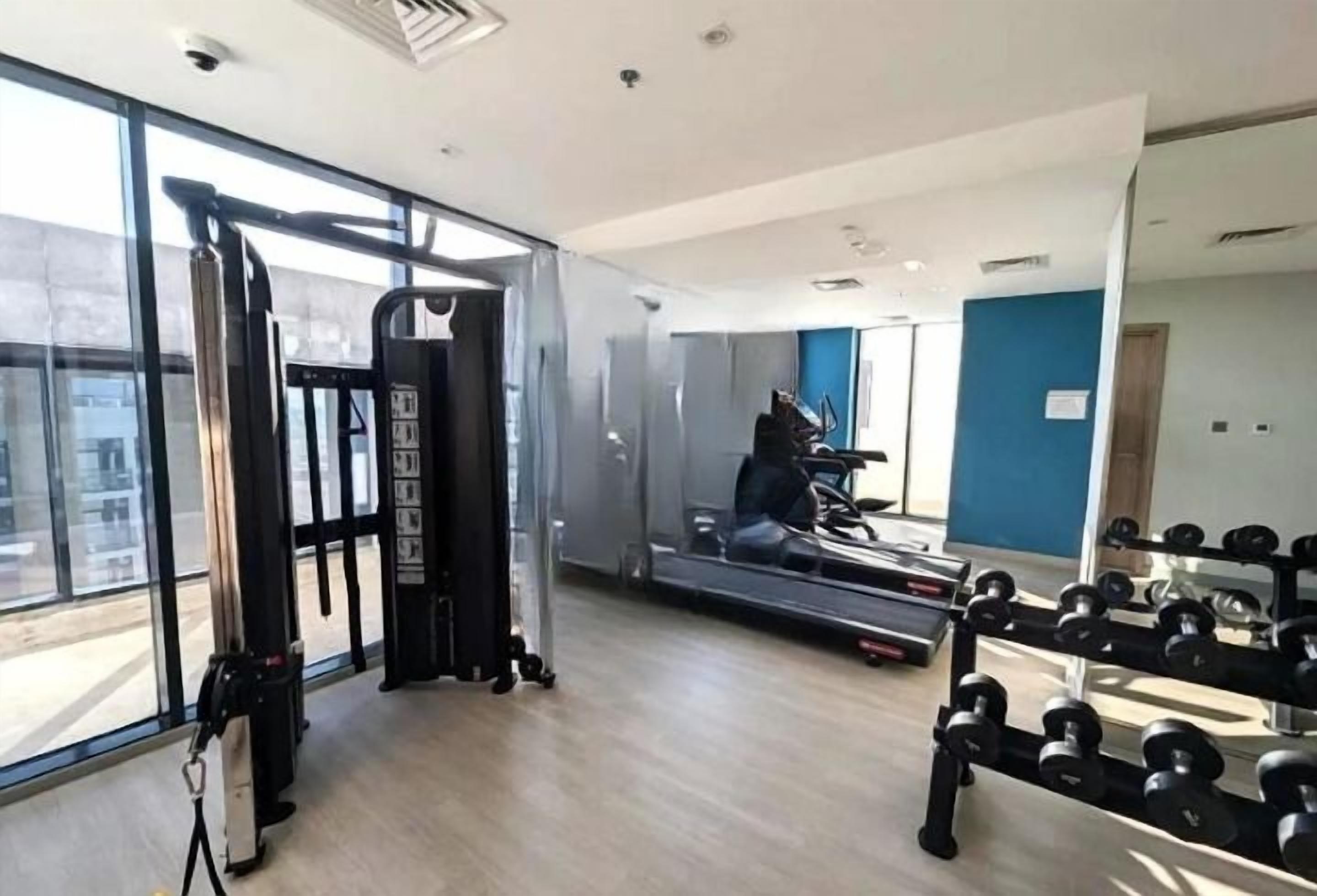 Ein Fitnessstudio mit Cardiogeräten, Krafttrainingsmaschinen und Kurzhanteln.