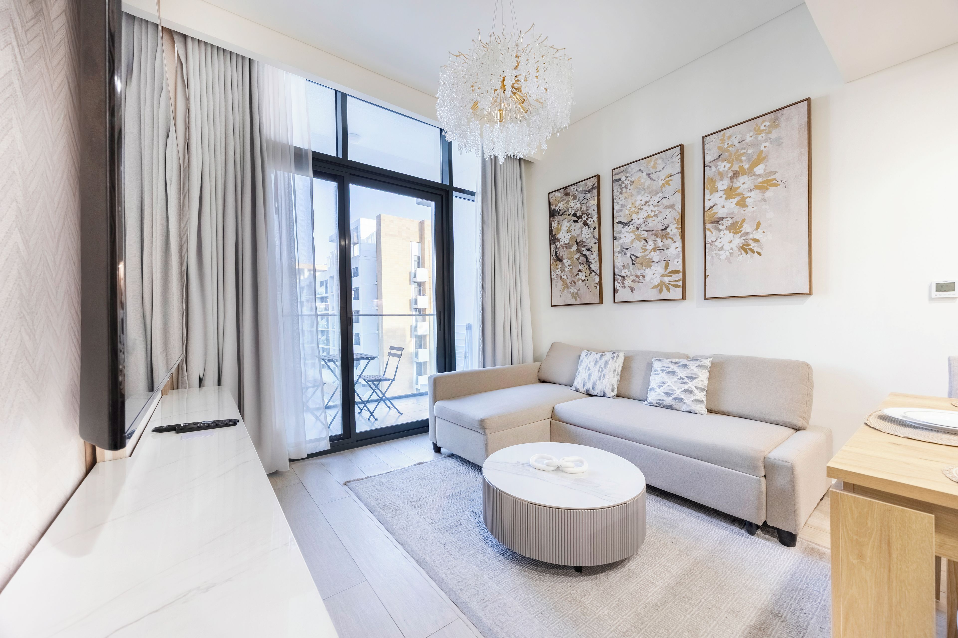 A modern living room with a sectional sofa, a round coffee table, and a large window with curtains.
