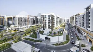 A modern urban residential area with multi-story buildings, a central roundabout, and a well-maintained road. - 520 Bloomfields 1BR Azizi Riviera (Dubai)