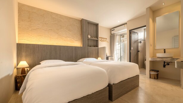 A modern hotel room with two beds, a large mirror, a built-in shelf, and a bathroom with a sink and shower. - Siam Escape (Bangkok)