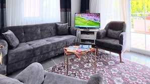 Una sala moderna con un sofá seccional gris, una mesa de centro y un televisor.