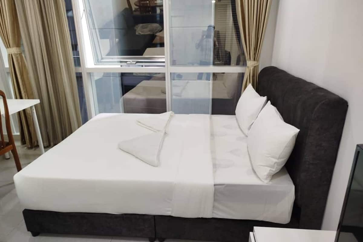 Un dormitorio moderno con una cama grande, un separador de vidrio y vistas al exterior.